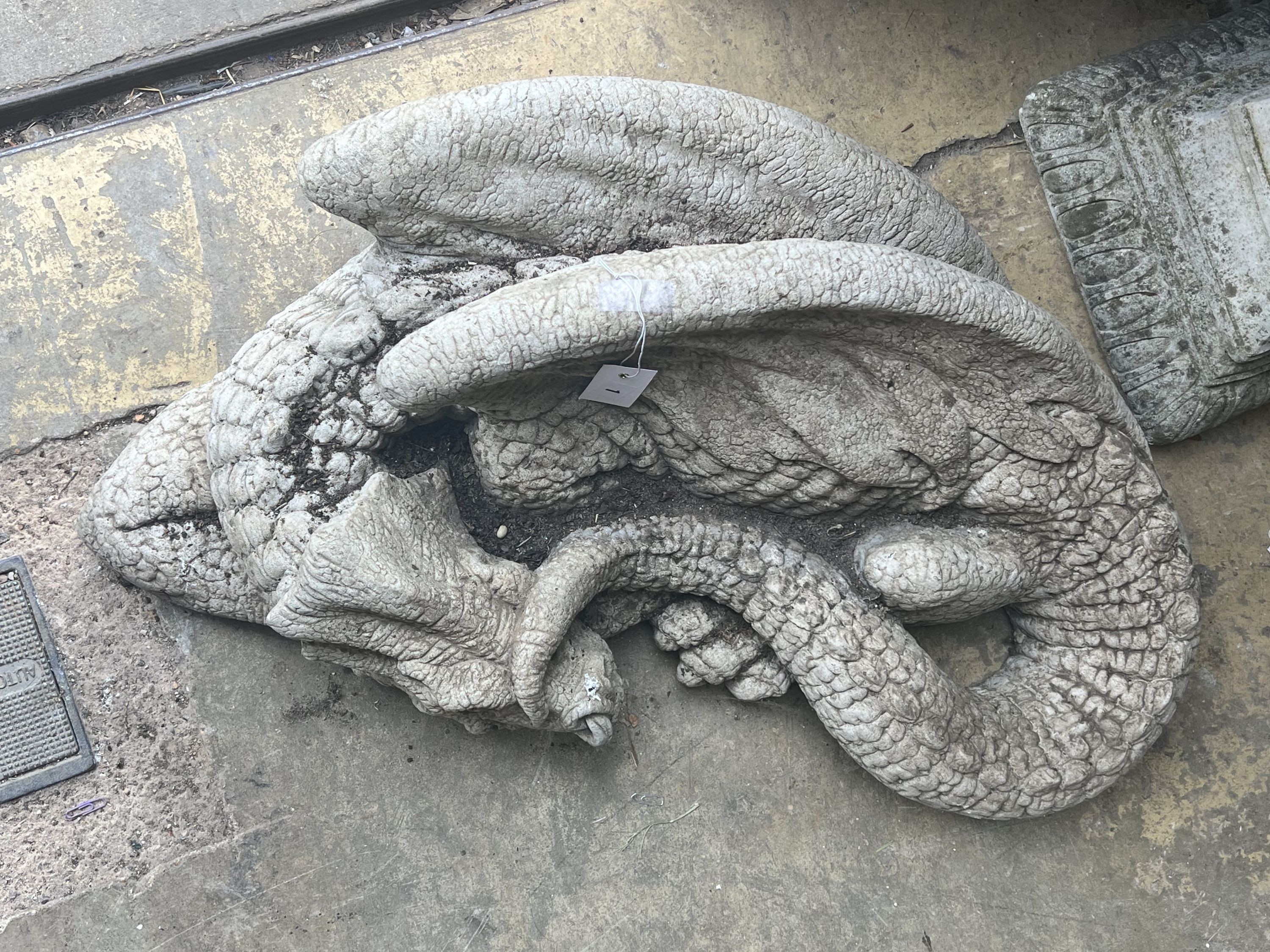 A reconstituted stone garden ornament of a sleeping dragon, width 80cm